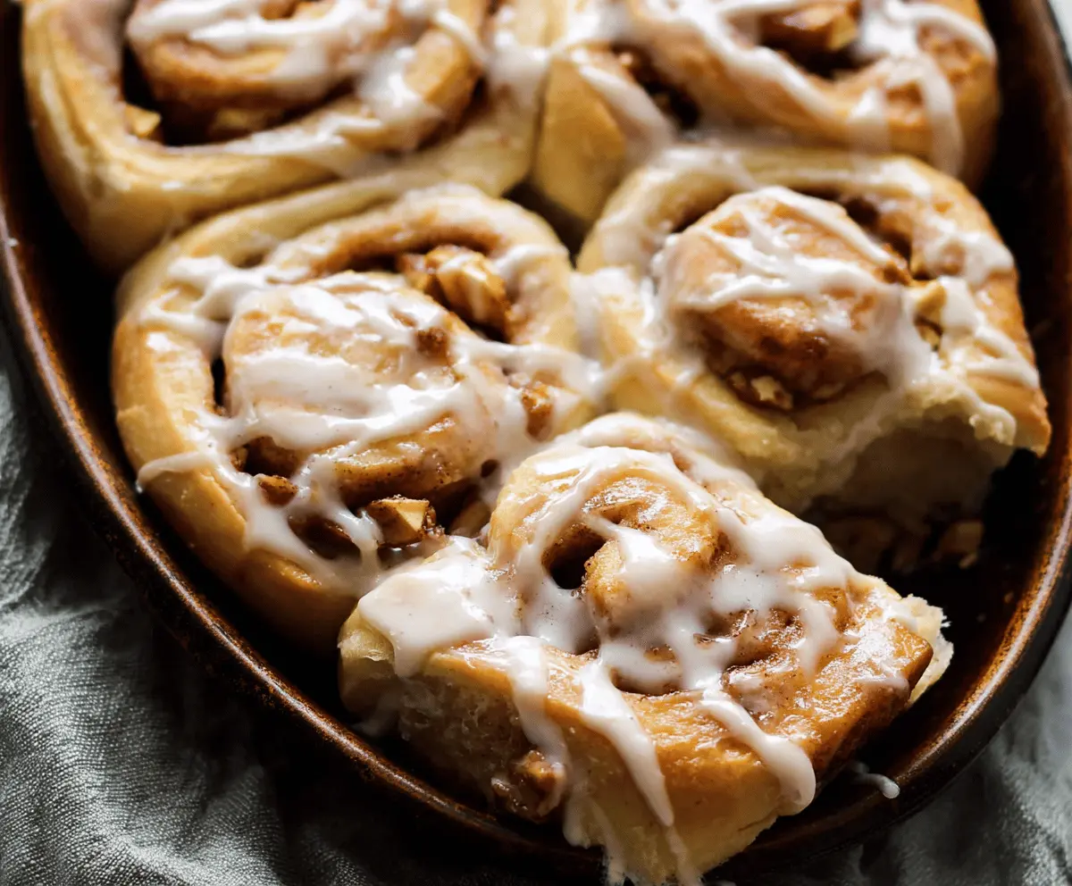 Delicious homemade apple cinnamon rolls topped with icing, featuring gooey apple filling and warm cinnamon spices, perfect for breakfast or dessert.