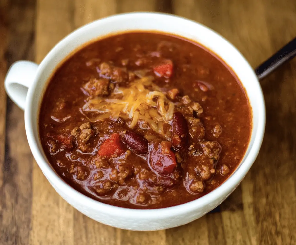 Delicious homemade Copycat Wendy's Chili served in a bowl with toppings on a rustic wooden table