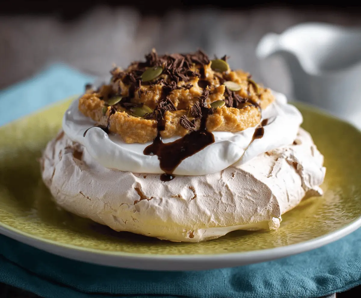 Delicious pumpkin pavlova topped with whipped cream and seasonal pumpkin decorations, perfect for fall dessert