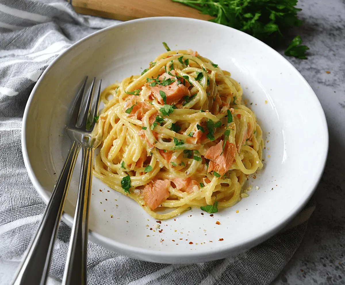 Creamy smoked salmon carbonara dish garnished with fresh herbs and black pepper, served on a white plate