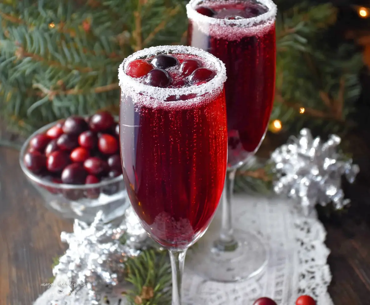 Festive Cranberry Christmas Mimosa with fresh cranberries and orange slices in a sparkling flute.