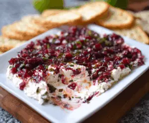 Creamy cranberry and jalapeño cream cheese dip garnished with fresh herbs, perfect for parties.