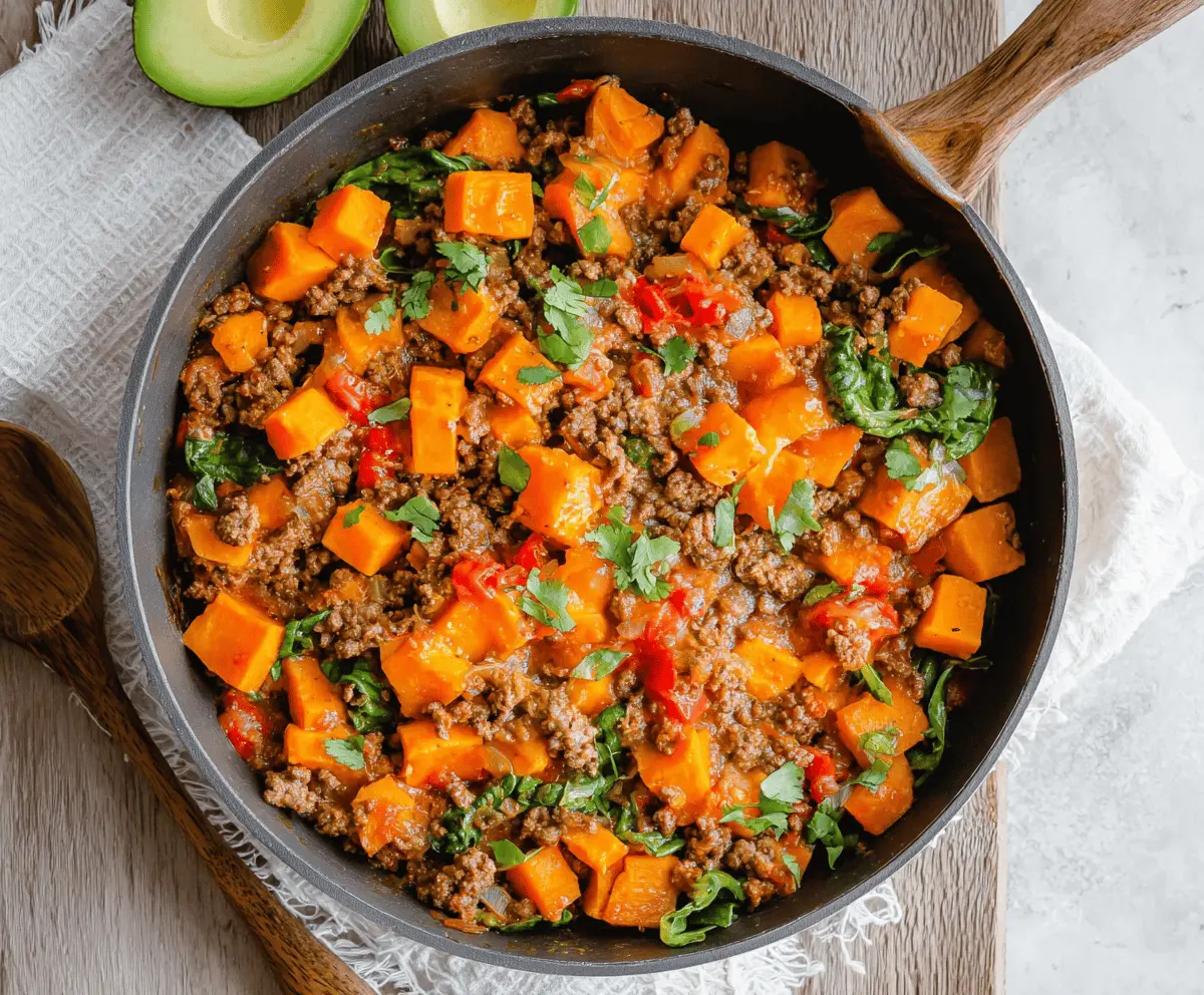 Delicious sweet potato and ground beef skillet served in a bowl, garnished with herbs.