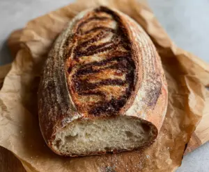 Close-up of freshly baked cinnamon swirl sourdough discard bread with a golden crust and visible cinnamon filling.