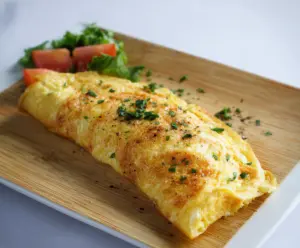 Delicious classic omelet with fluffy eggs and melted cheese on a white plate.