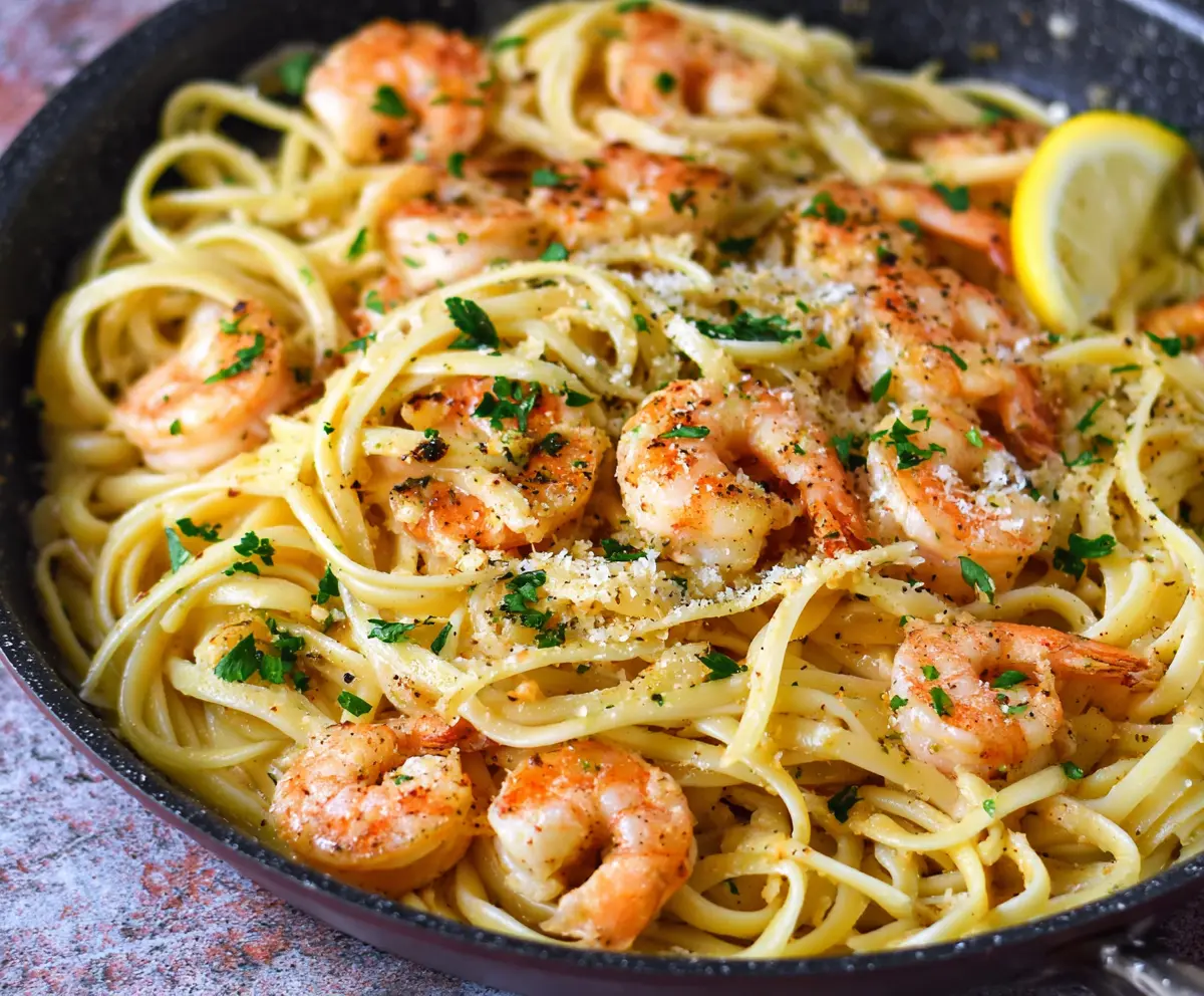 Delicious linguine shrimp scampi with garlic and lemon zest on a white plate.