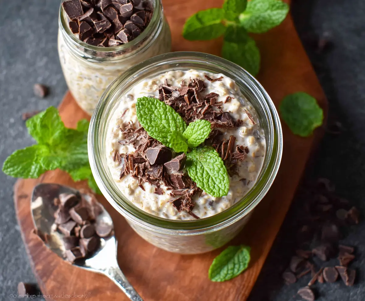 Creamy Mint Chocolate Chip Overnight Oats in a glass jar with fresh mint leaves on top