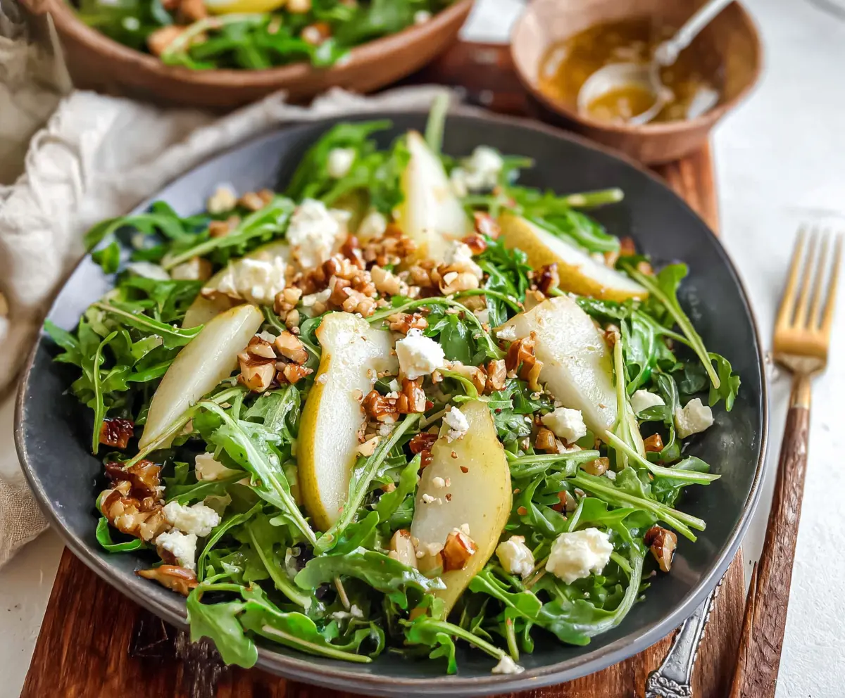 Fresh arugula and ripe pear salad with walnuts and blue cheese, served as a healthy appetizer.