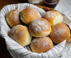 Freshly baked crusty sourdough dinner rolls on a rustic wooden table, perfect for a hearty meal.