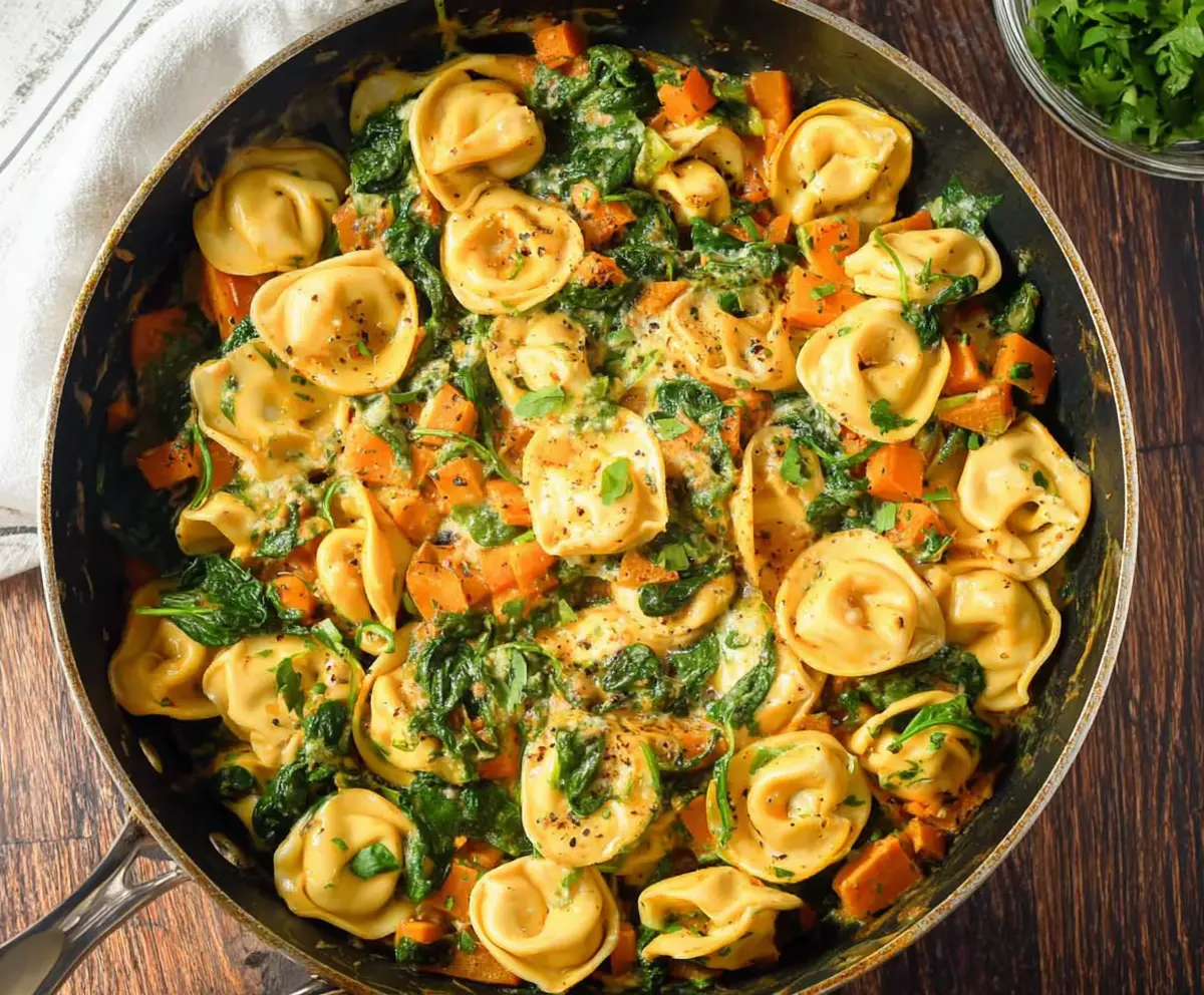 Delicious skillet tortellini with sweet potatoes and fresh spinach in a rustic dish.