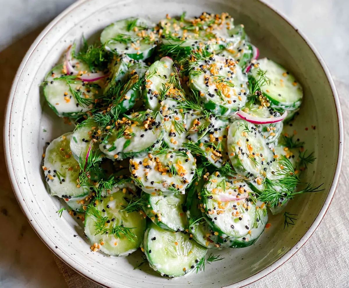 Refreshing cucumber and everything bagel salad with fresh ingredients on a white plate