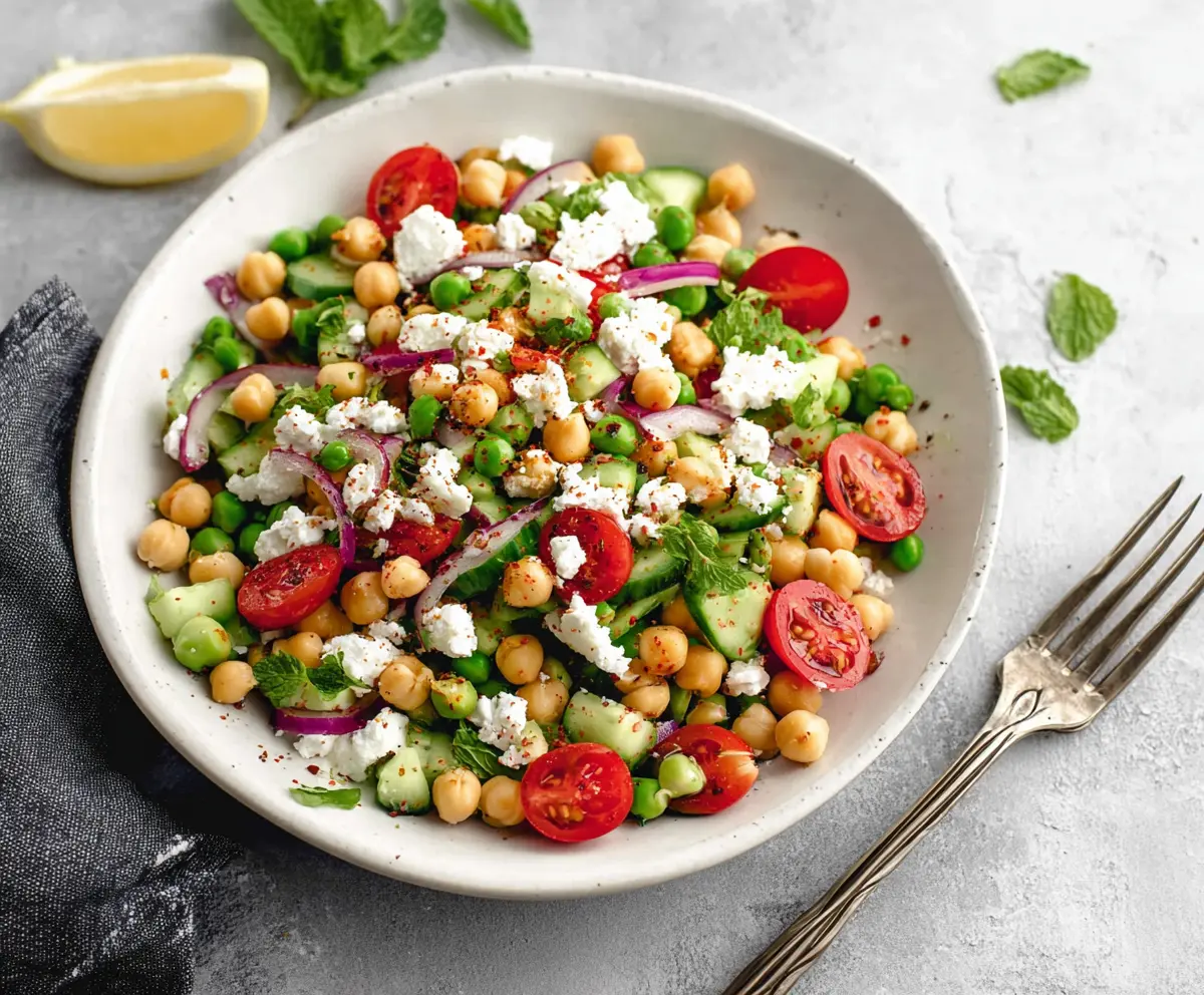 Fresh Mediterranean Pea Salad with feta cheese, tomatoes, and olives in a bowl