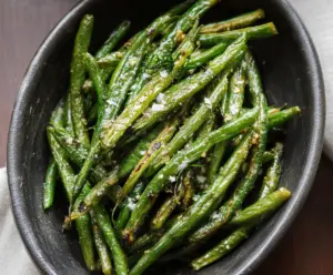 Delicious roasted green beans garnished with herbs on a white plate