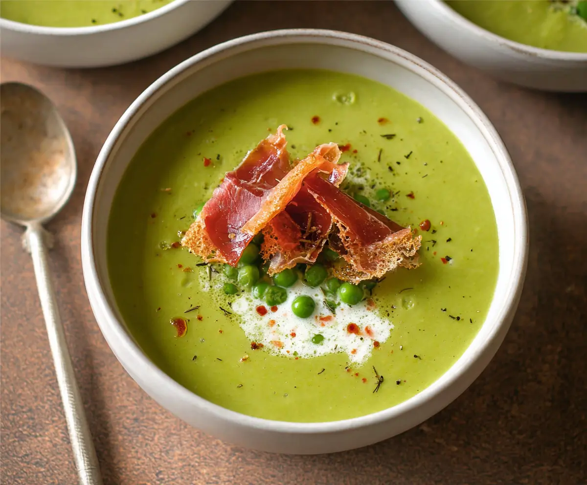 Savory spring pea soup topped with crispy prosciutto slices on a rustic plate.